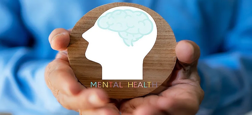 A person holding a wooden circle with a brain icon, symbolizing awareness of what is mental health.