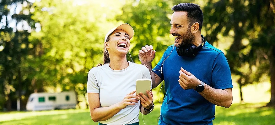 Happy sports couple laughing while exercising outdoors, showing how to maintain a healthy lifestyle together.